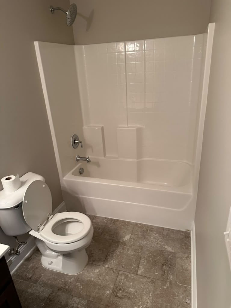 Hall bathroom tub area before the remodel, with an almond tub surround and beige tile floor