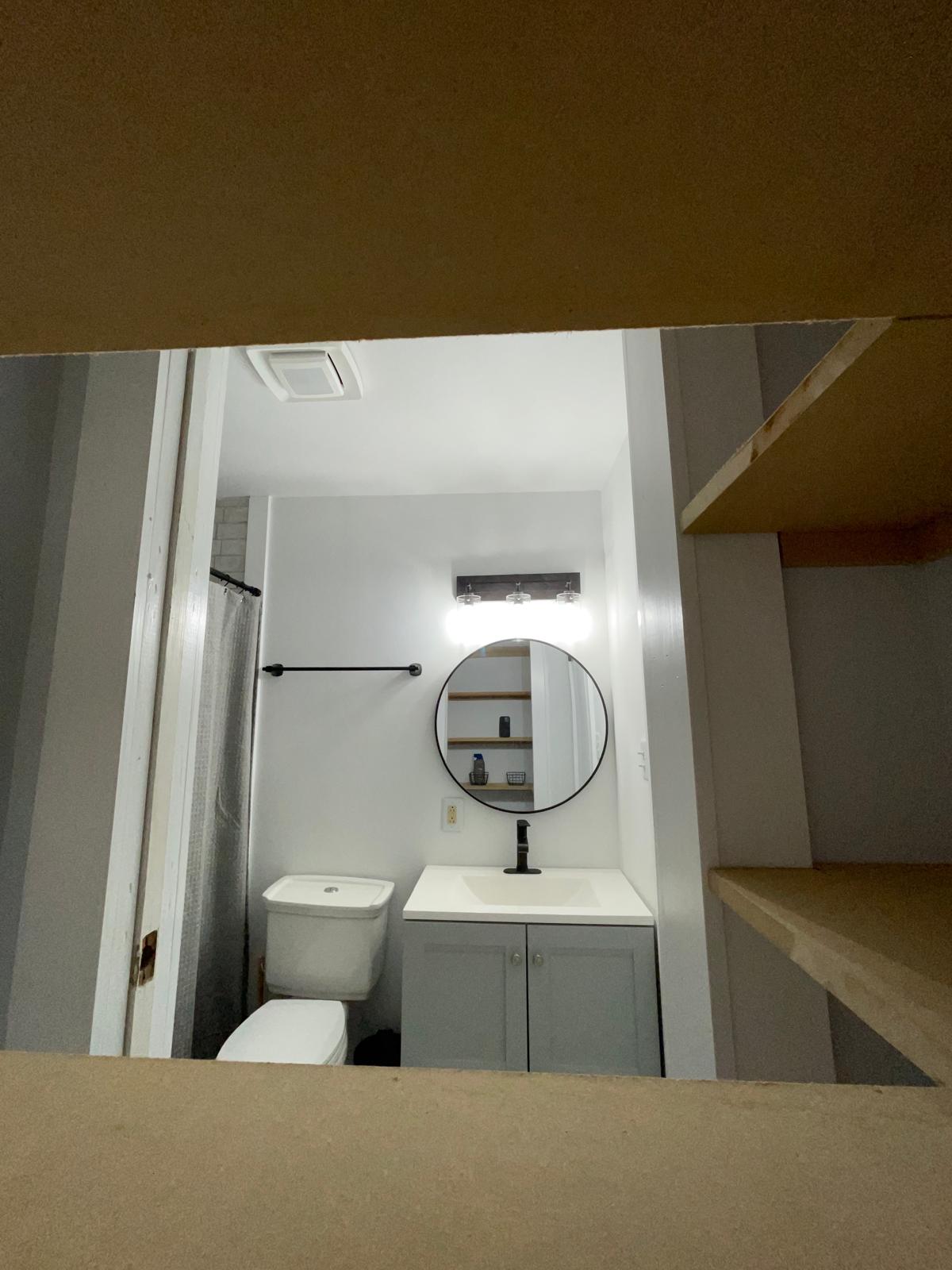 Finished guest bathroom seen through a framed doorway opening