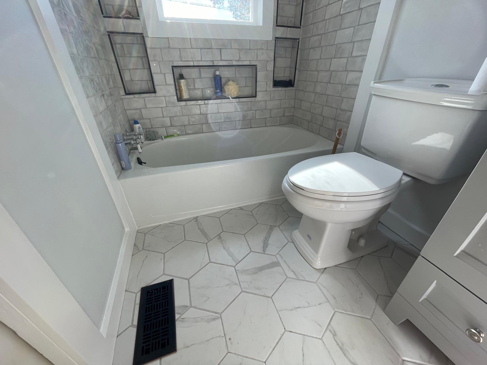 Guest bathroom tub with white subway tile surround and recessed niches