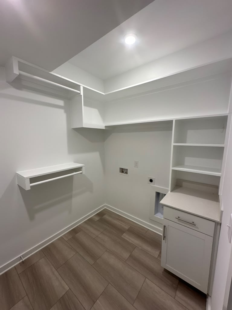 The finished laundry room with painted shelving, a hanging rod and a quartz-topped base cabinet