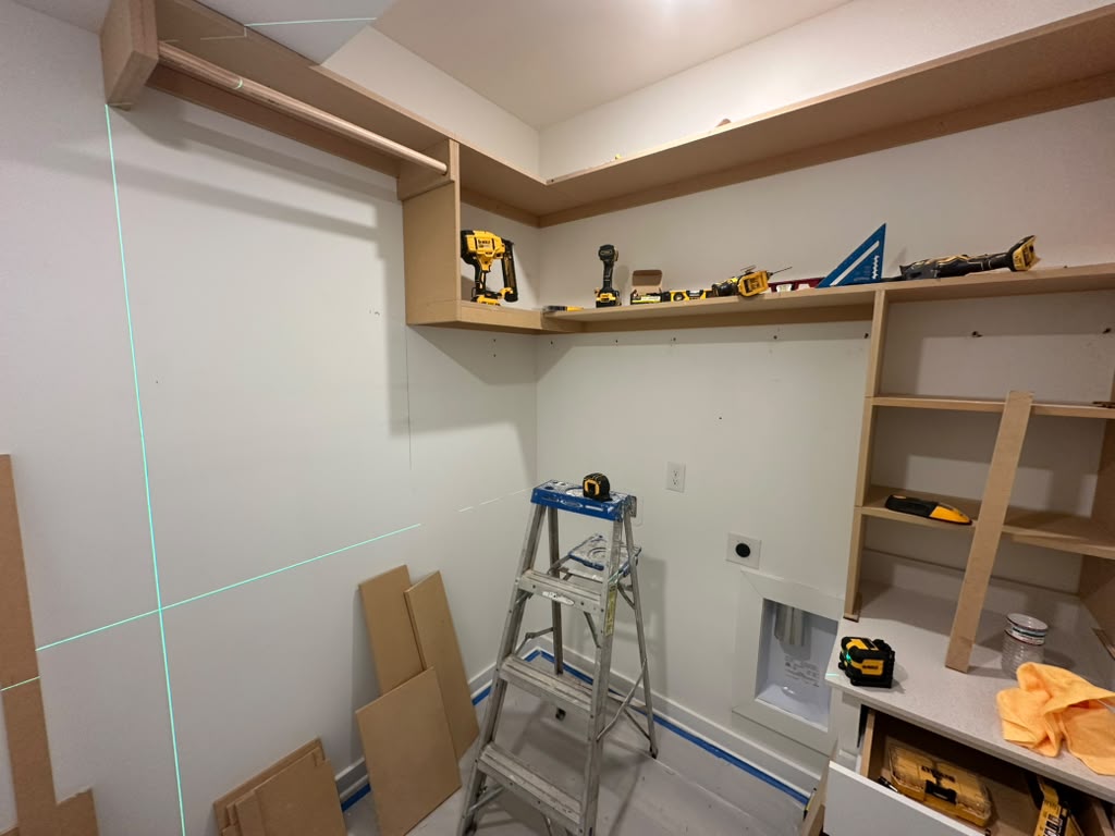 The laundry room shelving mid-install, with unpainted MDF shelves being fitted