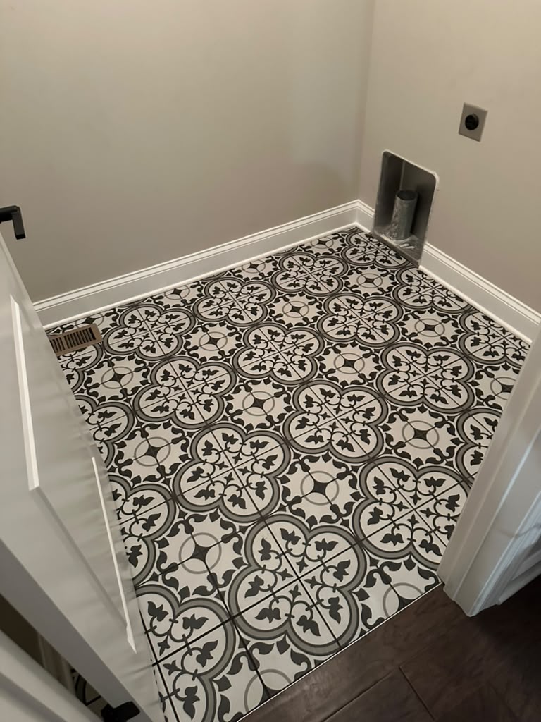 The same floor after replacement, with black and white patterned encaustic-style tile and new baseboard