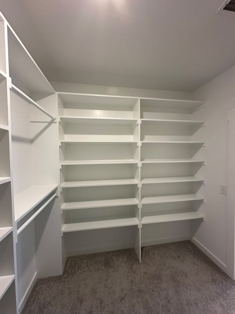 Walk-in closet with a bank of seven white shelves and a side tower